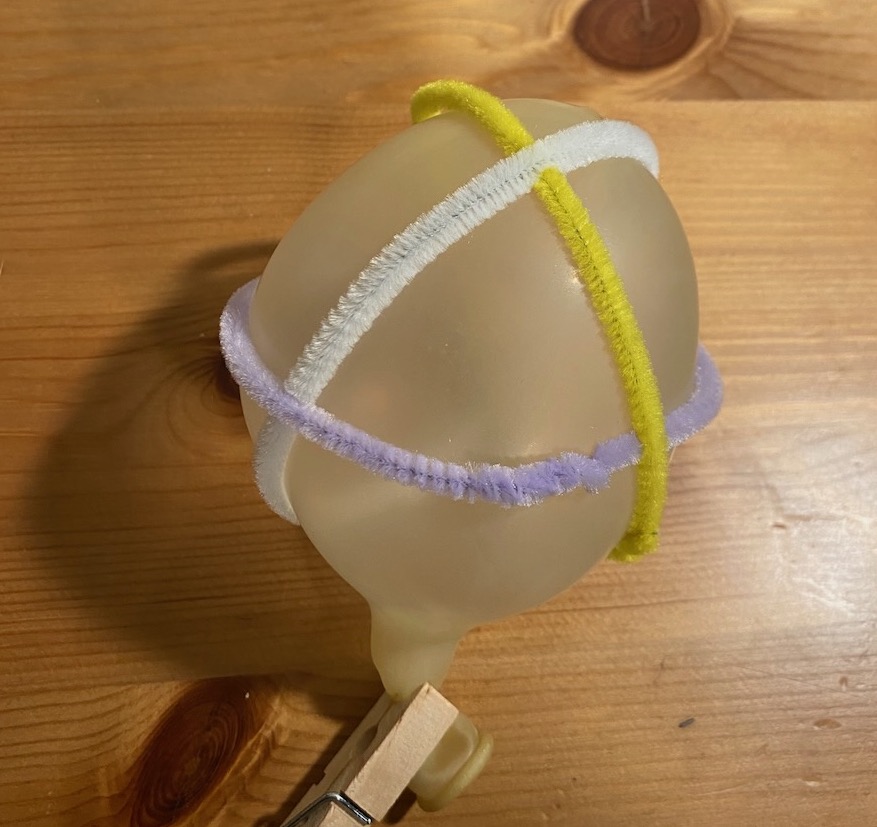 three pipe cleaners around a balloon, as the three equators