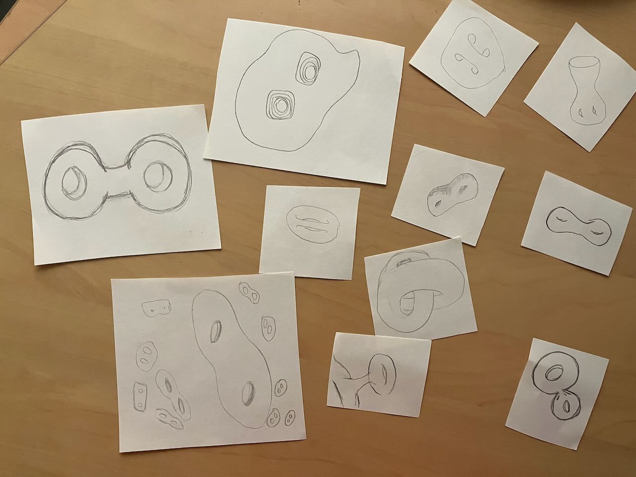 a collection of genus 2 surfaces of all sizes, drawn on small squares of paper