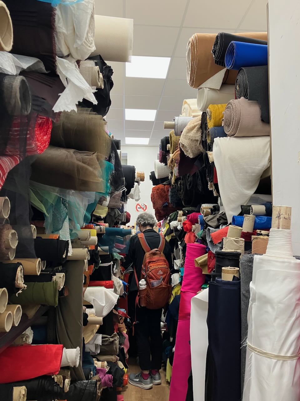 An extremly cramped store full of fabric floor to ceiling.