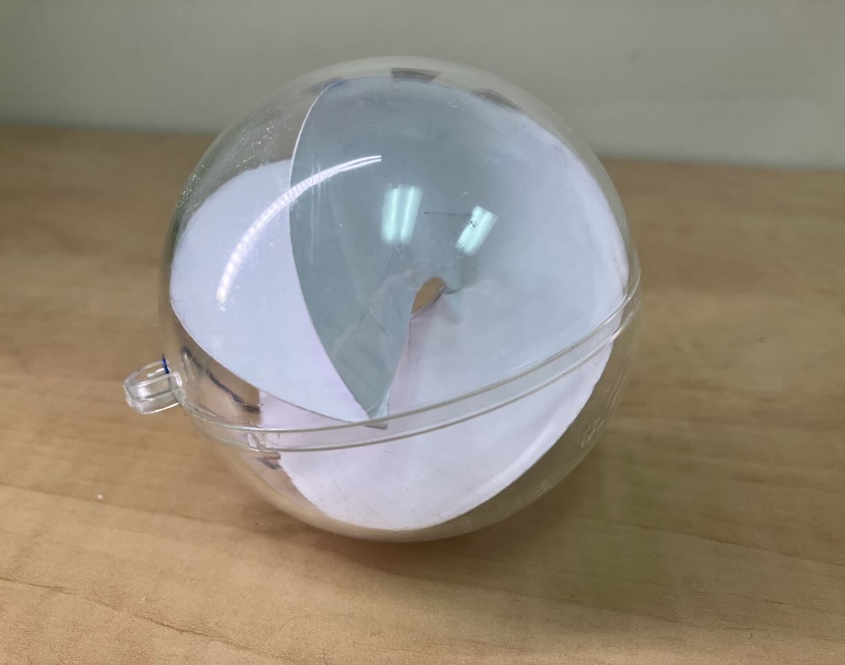 A christmas ornament, full of a contorting paper shape. It looks like a marble 