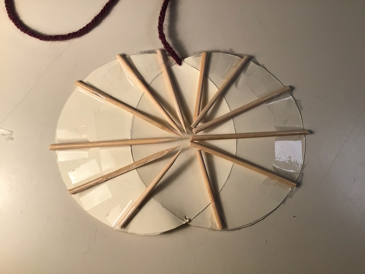 vesica piscis folded, with ruling lines extended using toothpicks. Each half clamshell has its lines of ruling, these toothpicks, all pointing at a single point. 